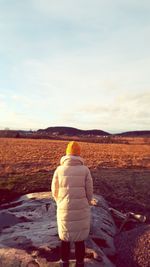 Rear view of woman looking at field against sky