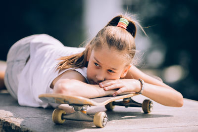 Portrait of cute girl sitting outdoors on skateboard