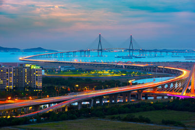 Light trails on bridge in city against sky at dusk