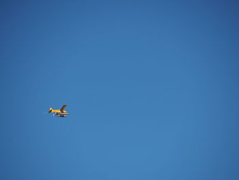 Low angle view of airplane flying against clear blue sky