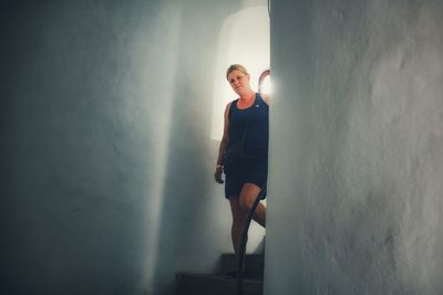 Portrait of young woman standing against wall