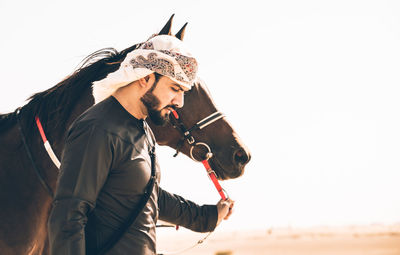 Side view man standing with horse in dessert