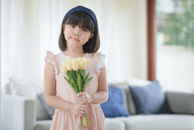 Girl holding flower at home