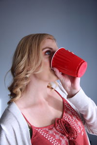 Close-up of beautiful woman holding red over white background