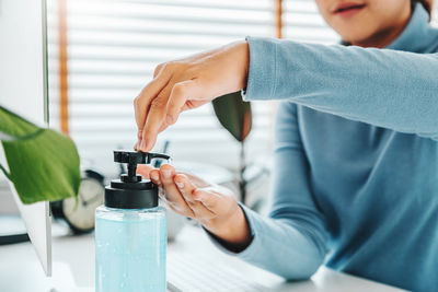 Midsection of man holding bottle on table