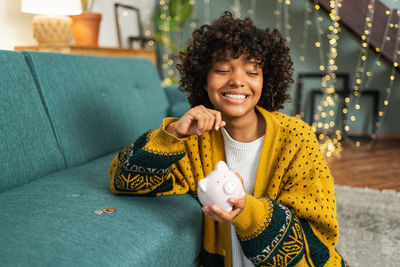 Portrait of young woman sitting on sofa at home