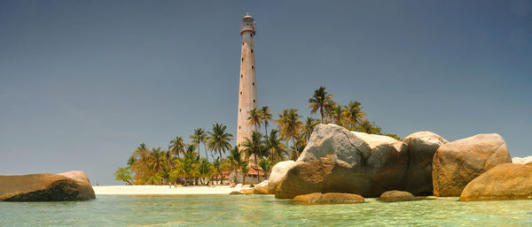 Rock formation by sea against clear sky