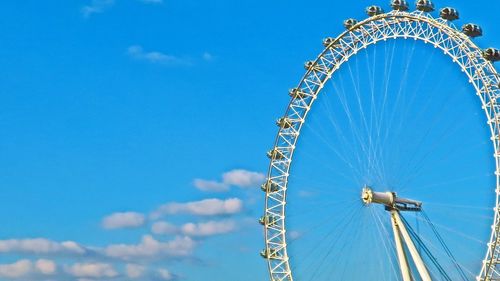 Low angle view of ferris wheel against blue sky