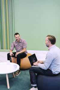 Happy businessmen conversing at modern office lobby
