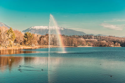 Scenic view of lake by mountains against sky