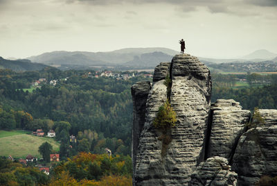 Man standing on rock against sky
