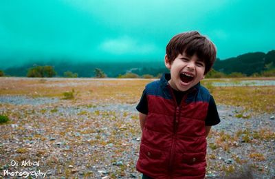 Boy standing on grass against trees