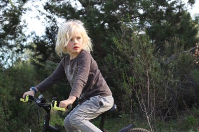 Side view of boy riding bicycle against trees