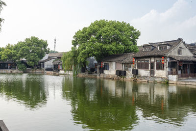 Buildings by lake against sky