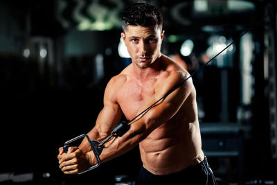 Portrait of shirtless man exercising in gym