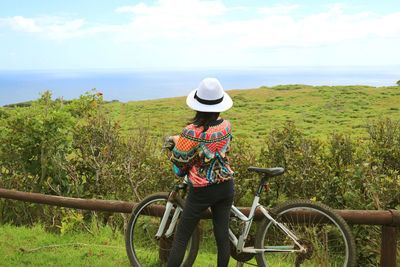 Rear view of person with bicycle on sea against sky