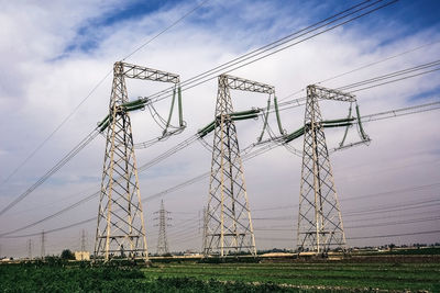 Low angle view of electricity pylon on field against sky