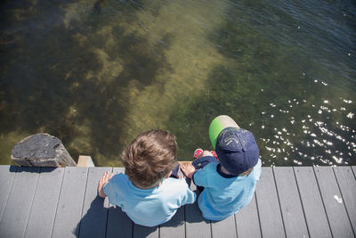 High angle view of two boys sitting on jetty