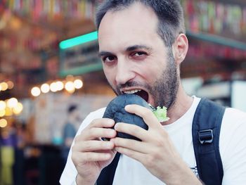 Close-up portrait of man eating burger