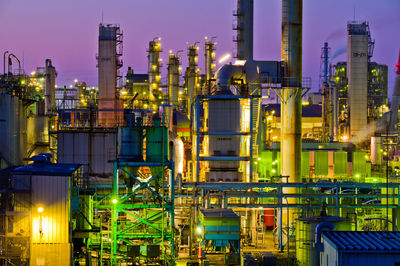 Illuminated factory against sky at night