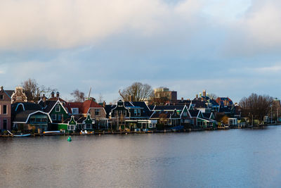 Scenic view of river by buildings against sky