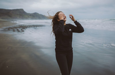 Woman standing at beach against sky