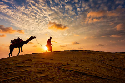 Silhouette people on beach against sky during sunset