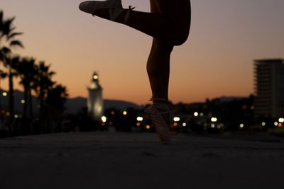 Low section of ballet dancer dancing on road in city