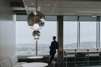 Rear view of businessman looking out through window at office