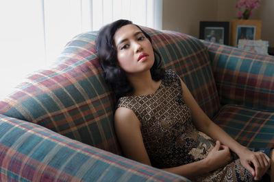 Portrait of mid adult woman sitting on sofa at home