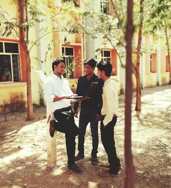 Friends standing by tree in front of building