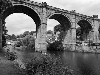 Arch bridge over river against sky