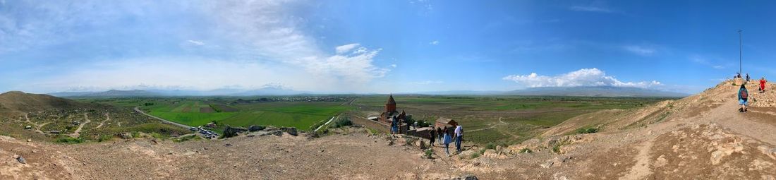 Panoramic view of people on landscape against sky