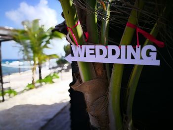 Close-up of information sign on beach against sky