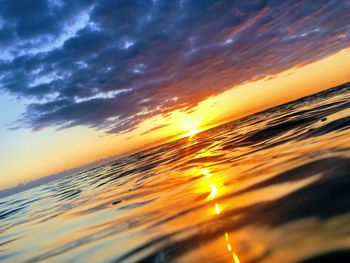 Scenic view of sea against dramatic sky during sunset