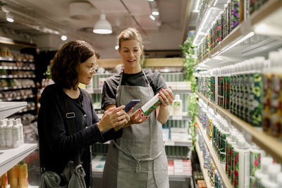 Saleswoman assisting female customer in supermarket