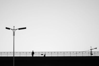 Silhouette man standing on bridge against clear sky