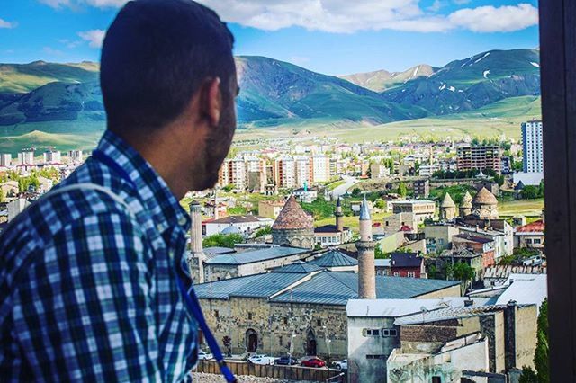 mountain, lifestyles, building exterior, leisure activity, mountain range, architecture, built structure, casual clothing, men, sky, railing, city, young men, waist up, day, cityscape, standing, looking at view