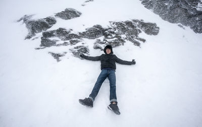 Full length of carefree man lying on snow