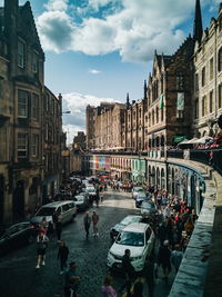 People on street amidst buildings in city against sky