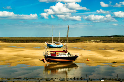 Fishing boats on shore against sky