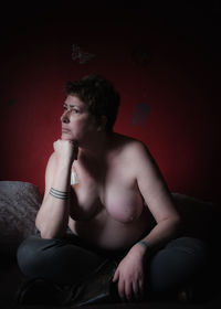 Young man looking away while sitting on sofa