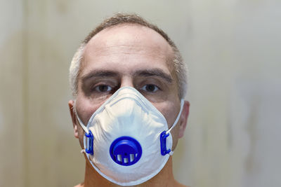 Portrait of man wearing flu mask sitting at home