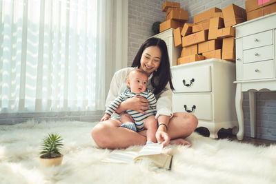 Mother reading book to toddler while sitting on fur at home