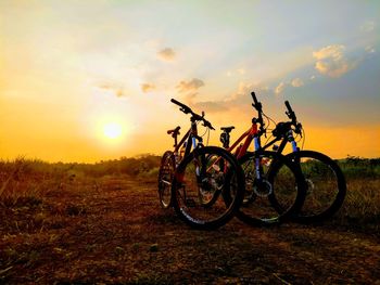 Bicycles on field against sky during sunset