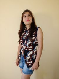 Woman looking up while standing against wall