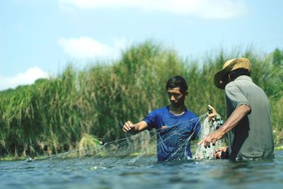 Men sitting on shore against sky