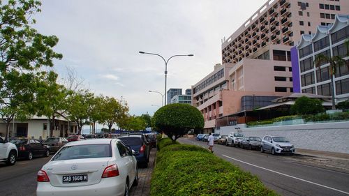 Cars on street by buildings in city against sky