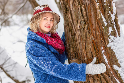 Portrait of smiling young woman standing against tree