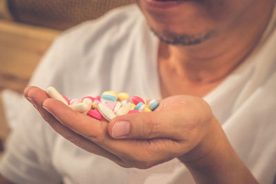 Midsection of man holding multi colored pills
